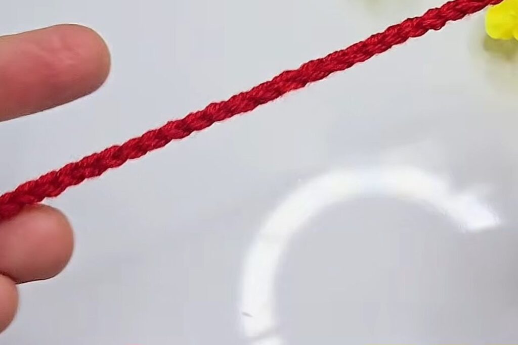 A red chain of 46 stitches for the crochet flower with stem petal strip