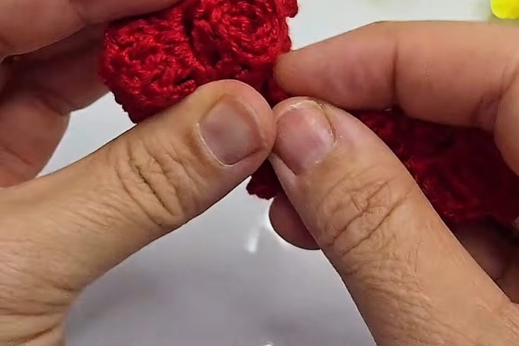 Rolled centre of the crochet rose being sewn at the base