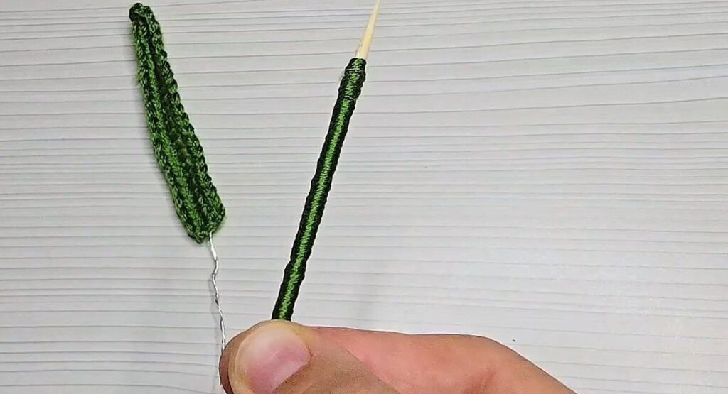 Skewer wrapped in green yarn beside the wired leaf