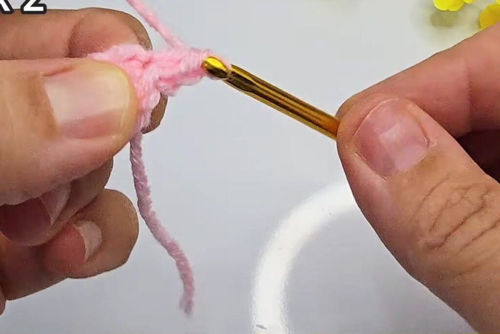Round 2 increases on a small pink crochet rosebud circle