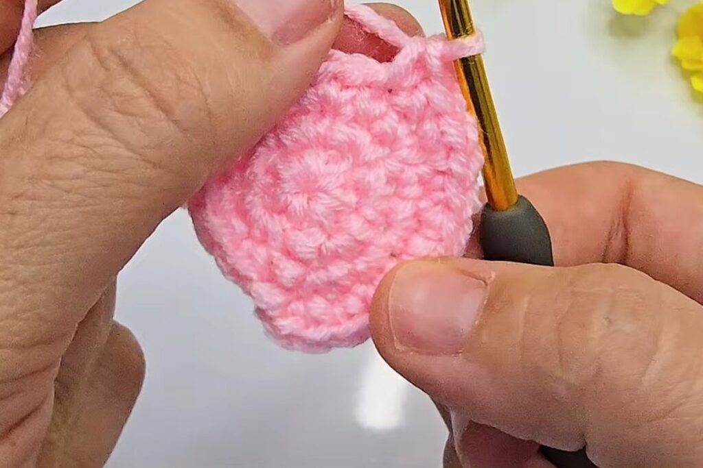 Working round 4 of a pink crochet rosebud circle