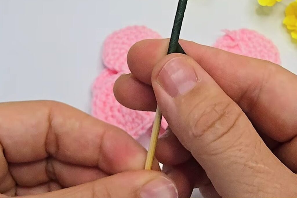 Green tape being wound round the skewer for the crochet rosebud stem