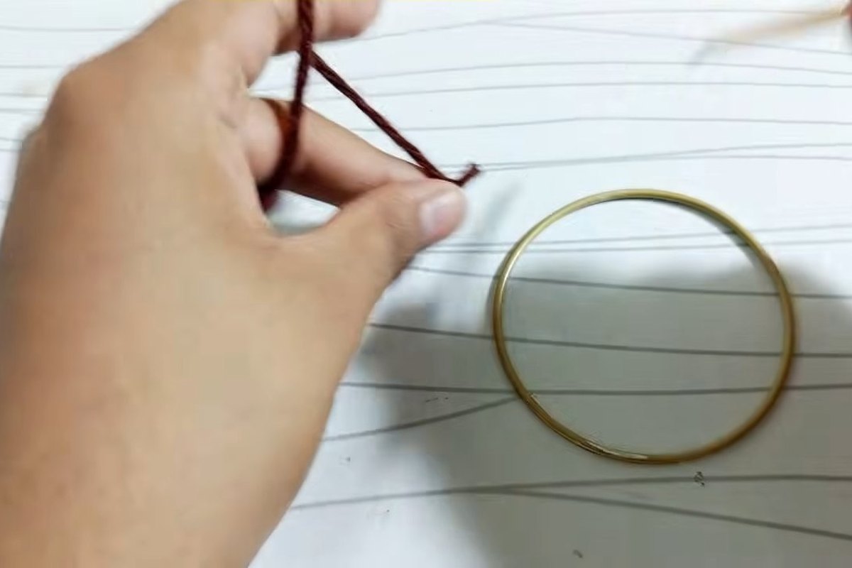 A loop of brown yarn beside the metal ring before the first stitch