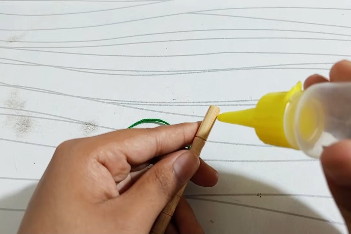 Putting craft glue on the tip of a wooden stick before wrapping