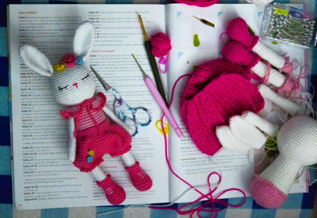 Amigurumi dolls with embroidered facial features resting on an open pattern book