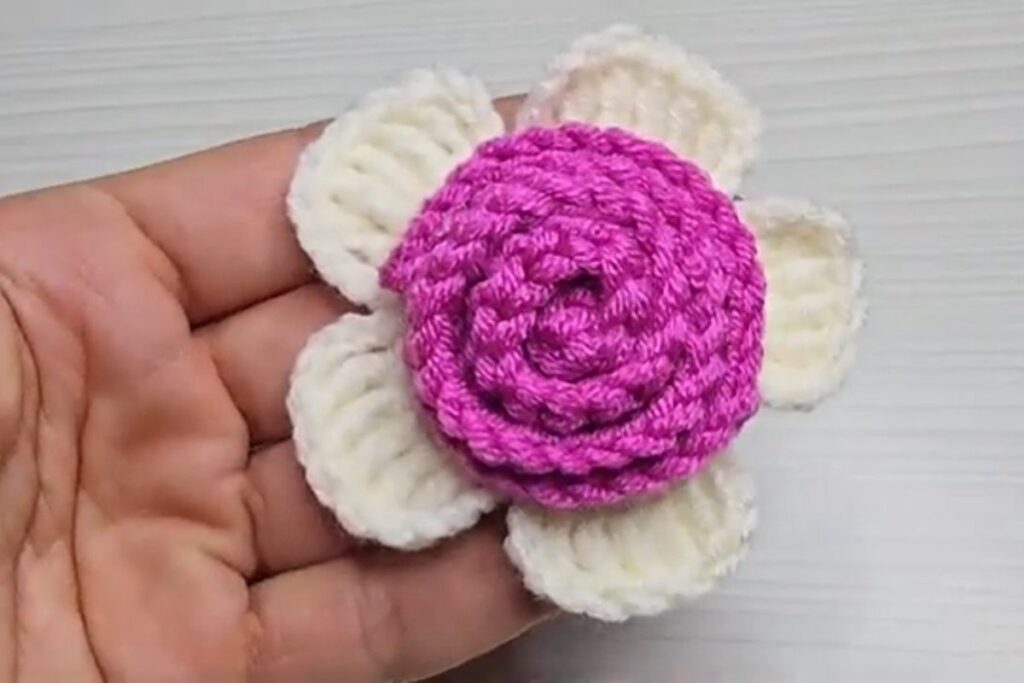 Finished layered crochet flower held in the hand, pink rose on white petals