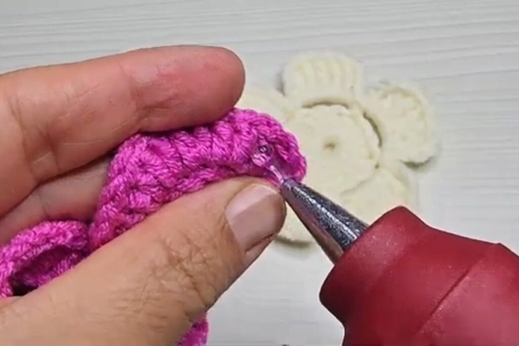 Hot glue added along the base while rolling the rose of a layered crochet flower