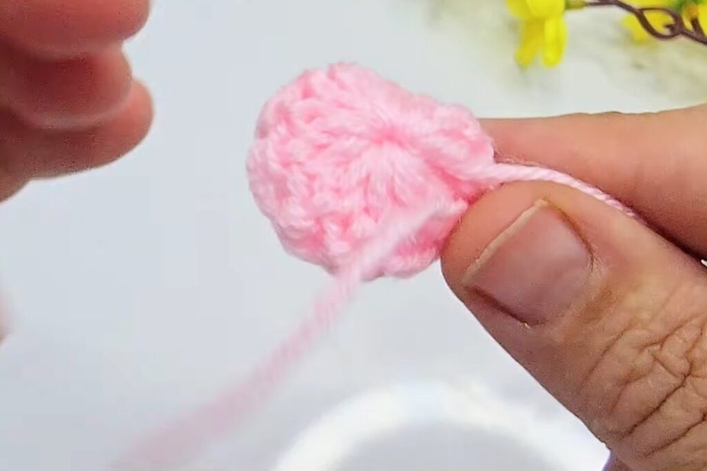 Flat pink crochet circle of 12 stitches after round 1