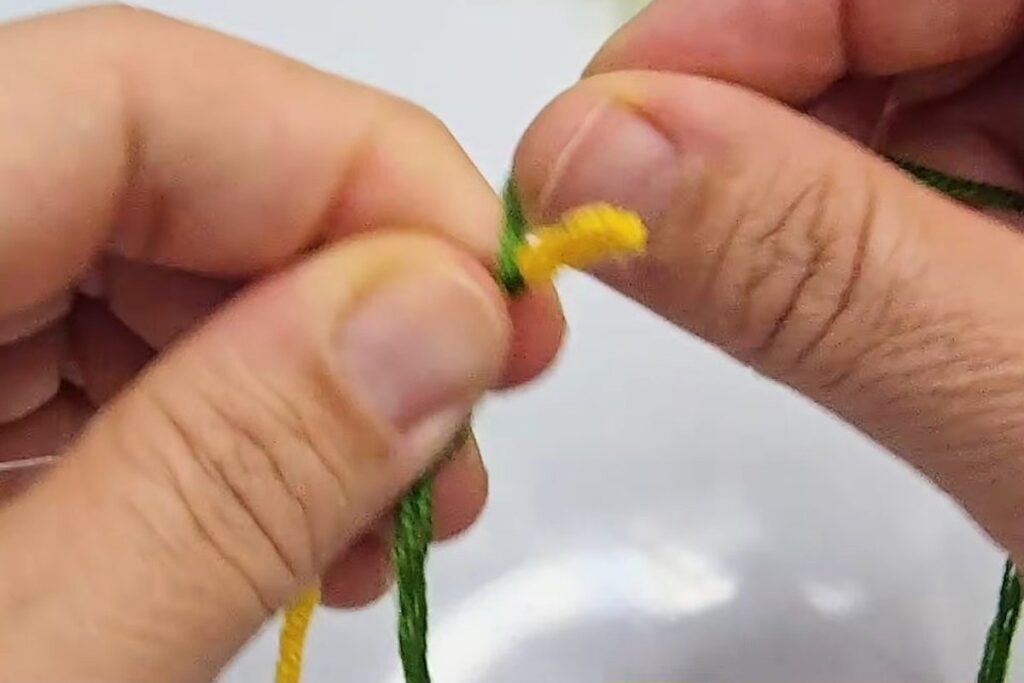 Green thread being wrapped tightly around the wire under the yellow tip