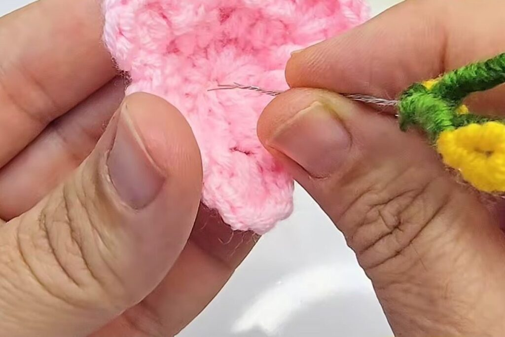 Stamen wires being pushed down through the centre of the pink crochet blossom