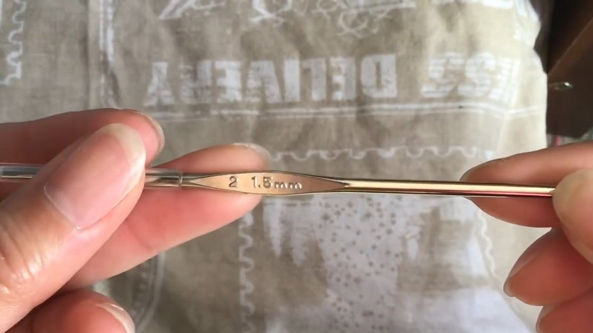 Steel crochet hook held between two fingers with 1.5 mm stamped on the handle for the crochet forget me not flower