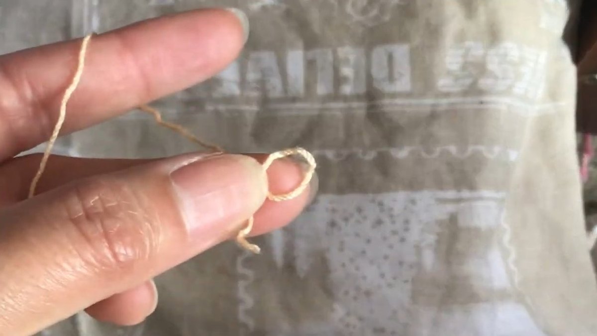 Peach thread wound in a loop round a fingertip to begin the centre of the crochet forget me not flower