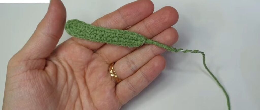 Finished green wired leaf for a crochet lavender flower held in the palm