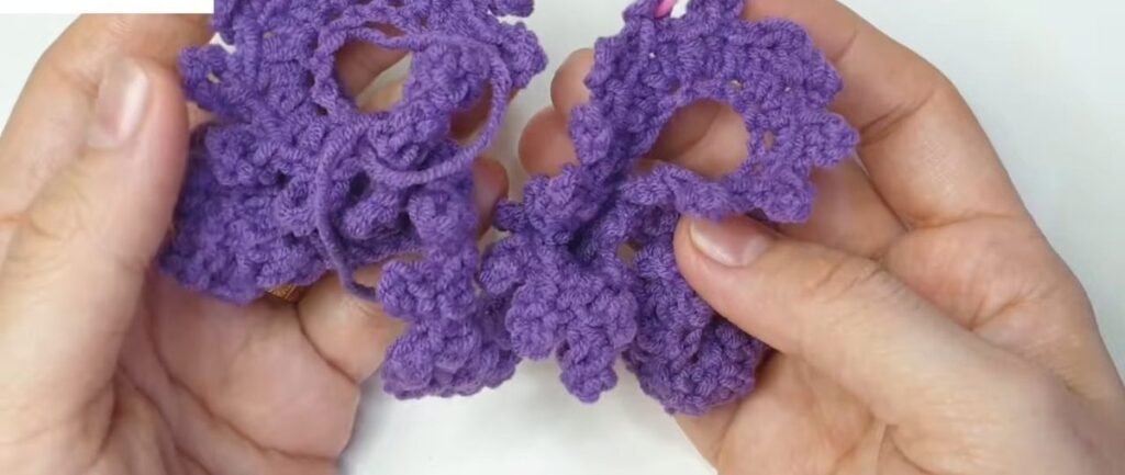 Finished purple crochet lavender flower strip coiled into a tight spiral in two hands