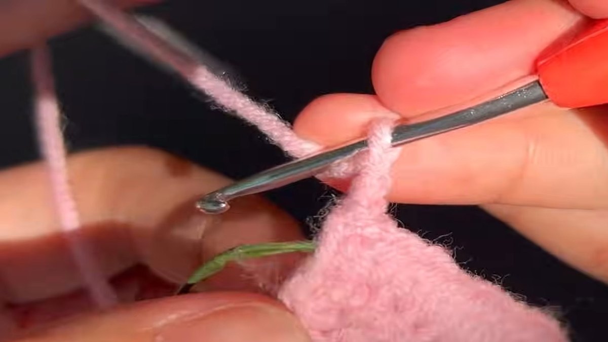 Hook working the pointed tip of a crochet lily flower petal with wire alongside