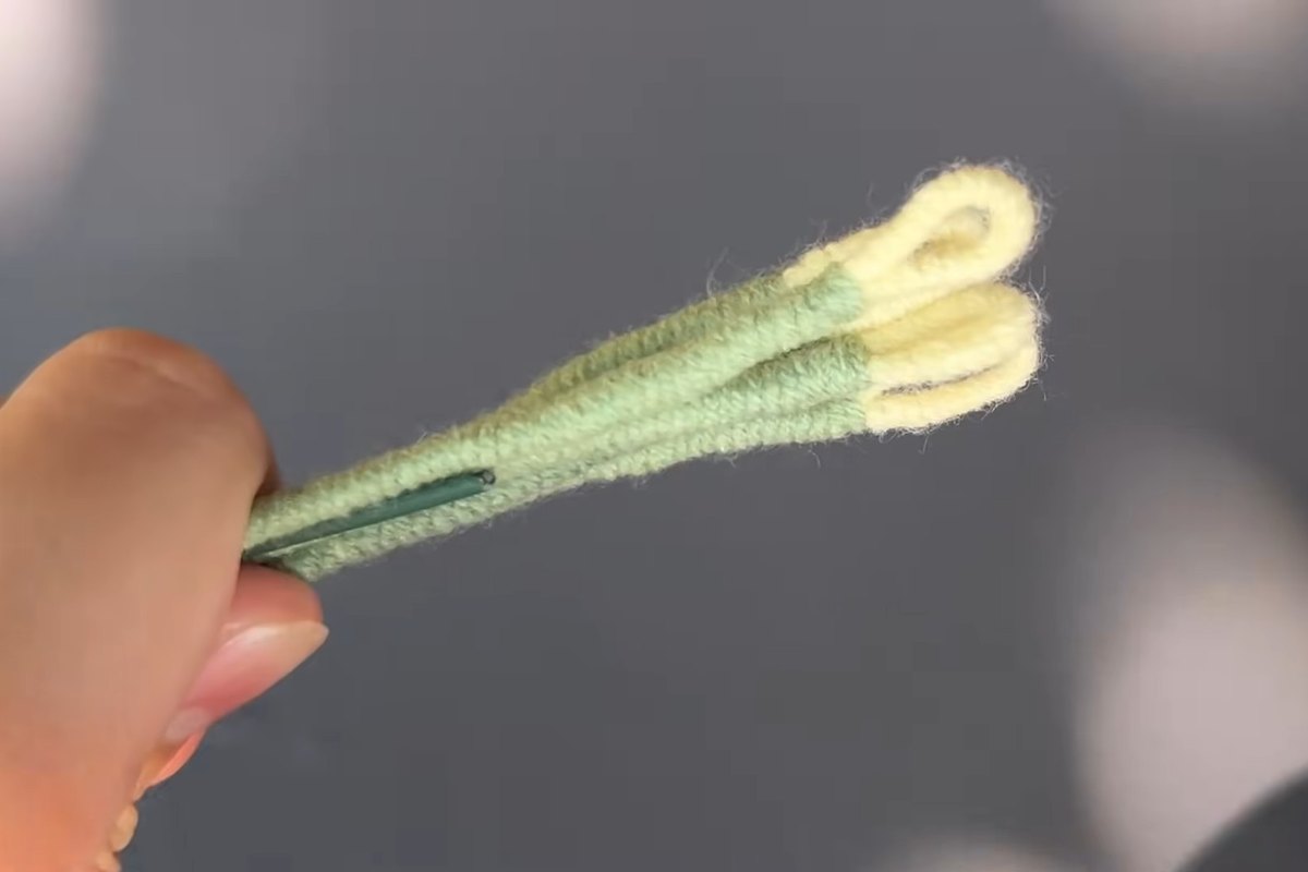 Yellow loops bundled and wrapped in green yarn to form the stamens of a crochet lily flower