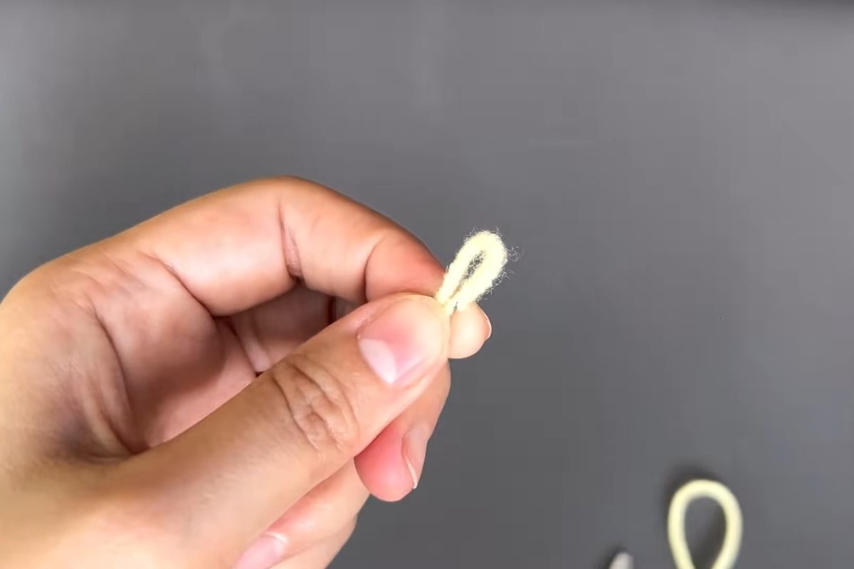 Small loop of yellow yarn held between two fingers for a crochet lily flower stamen