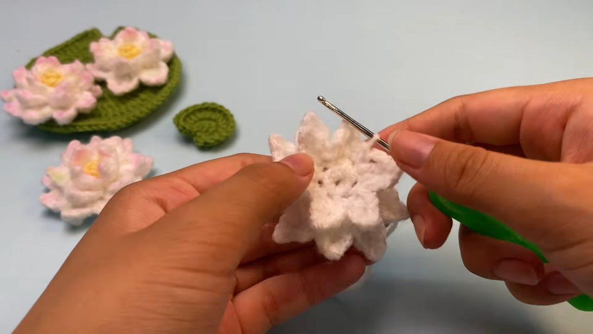 Crochet lotus flower seen from above with two layers of petals around the middle