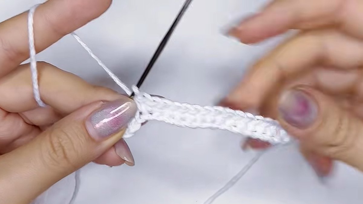 Longer white strip of single crochet stitches hanging from the ring for the large crochet magnolia flower