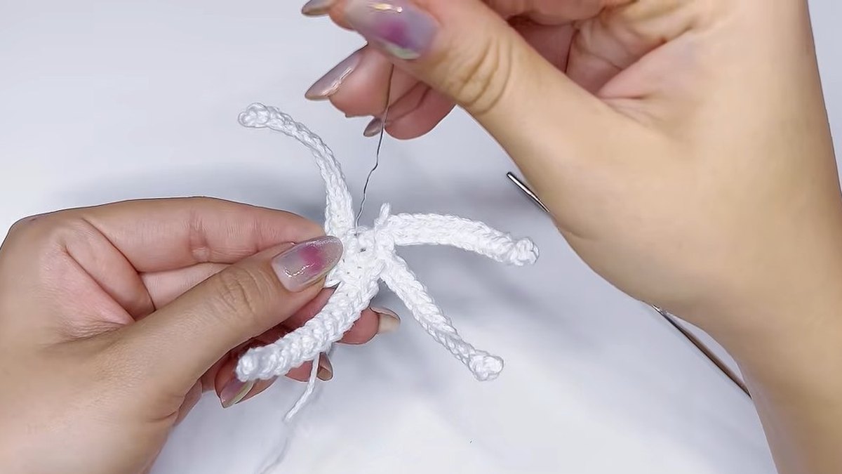 Five white crochet strips fanning out from a small ring, the base of the small crochet magnolia flower