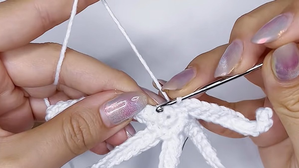 Wire laid through the middle of the small crochet magnolia flower with a hook making a slip stitch at that point