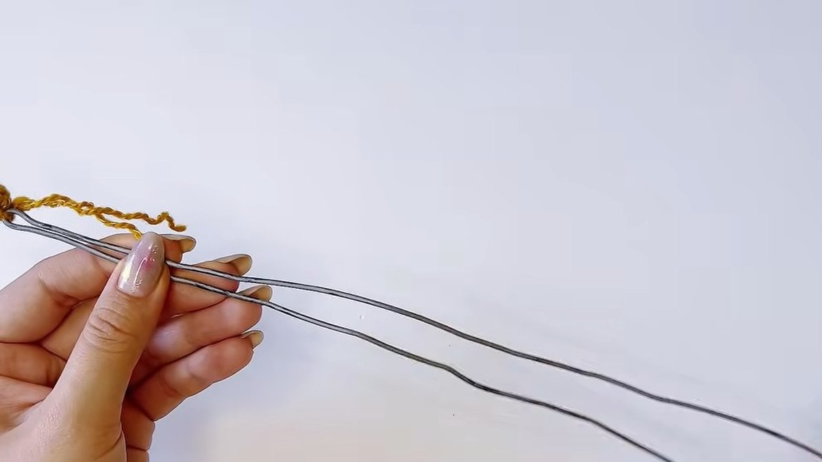 Two ends of a thin wire passing through a small gold crochet pistil for the crochet magnolia flower